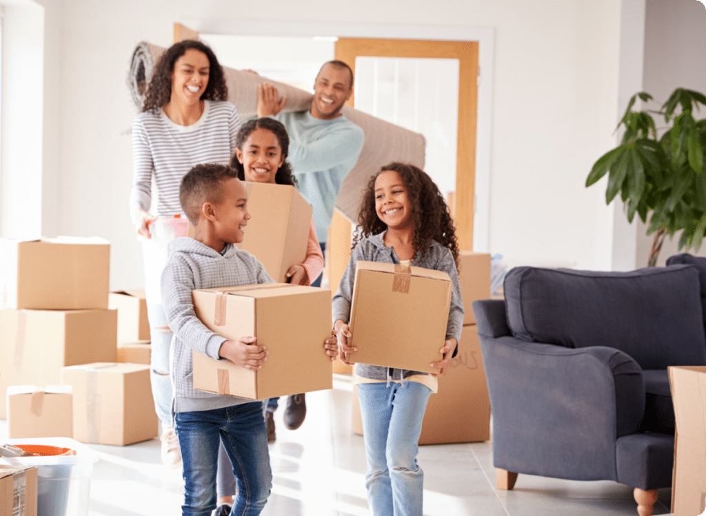 Young family with kids carrying boxes into their new house