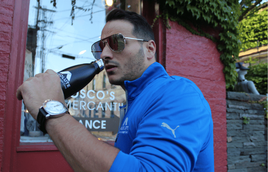 Young man wearing Absolute Home Mortgage sweatshirt and drinking from an Absolute Home Mortgage water bottle