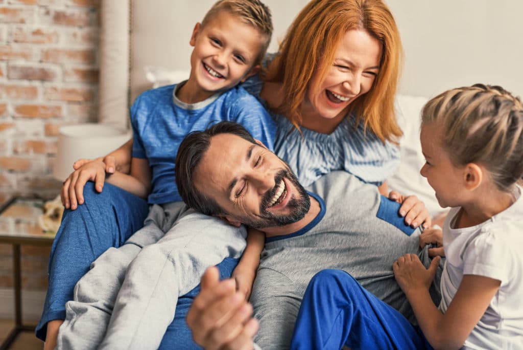 Happy family lying down on bed at home