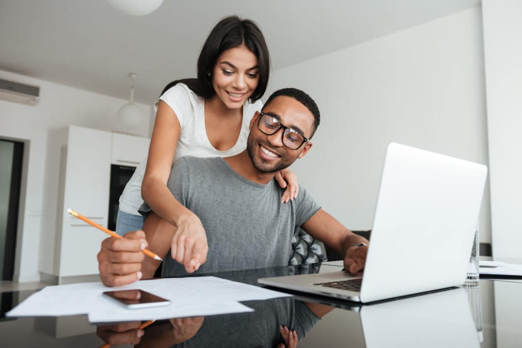 Loving young couple using laptop and analyzing their finances