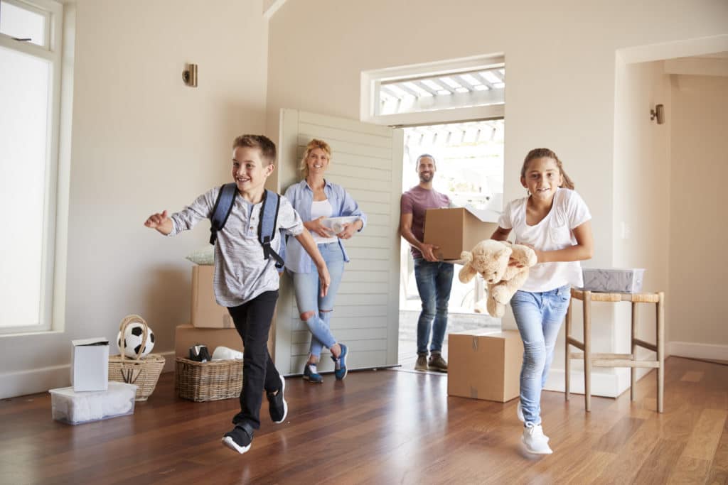 Excited Family Carrying Boxes Into New Home On Moving Day