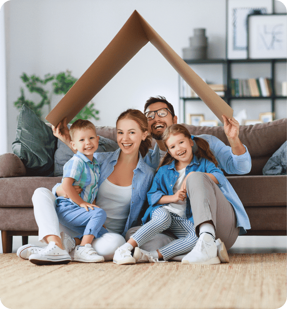 Happy family sitting on the floor with dad holding cardboard box over them like a rooftop
